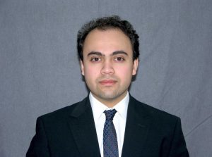 Portrait of Kieran in a suit against a blue background