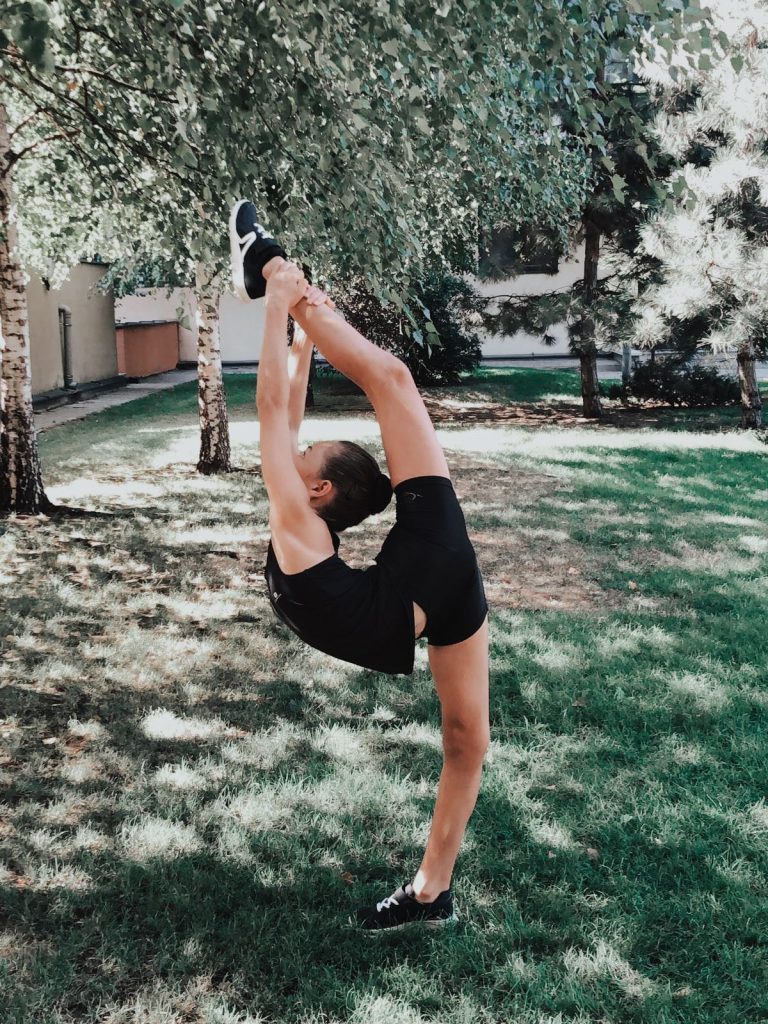 Student, Ava doing a gymnastic floor pose outside in a garden