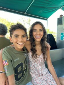 A young girl and young boy smiling with their arms around each other
