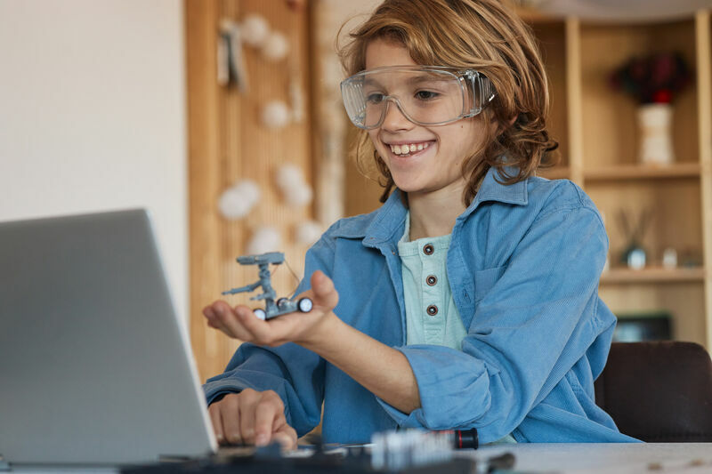 School boy, working on his prototype of a robot at home.