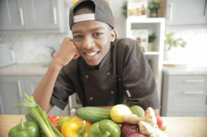Young student wearing chefs clothing smiling in his kitchen